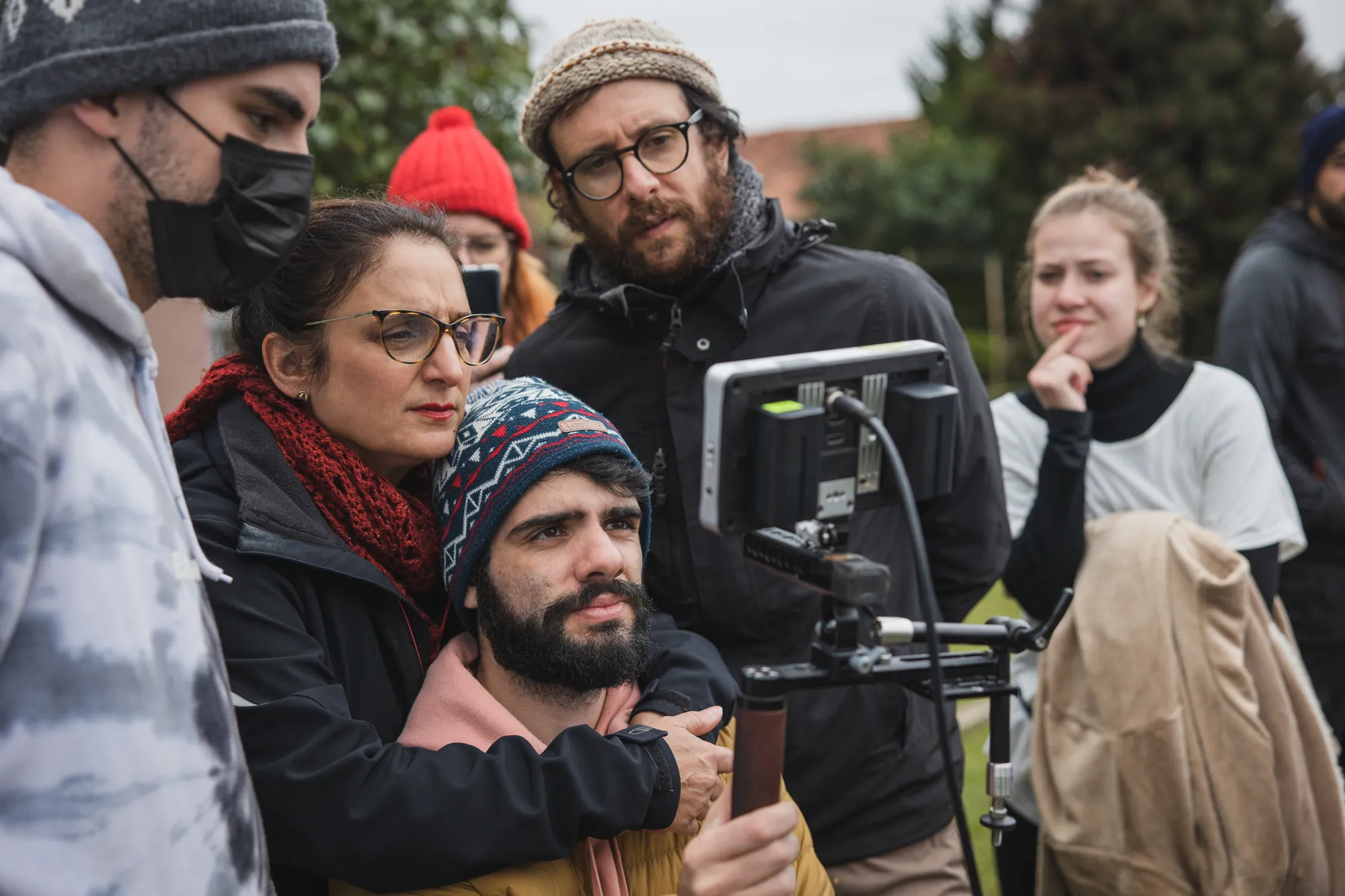 Equipe de filmagem ao ar livre, com a direção acompanhando pelo monitor