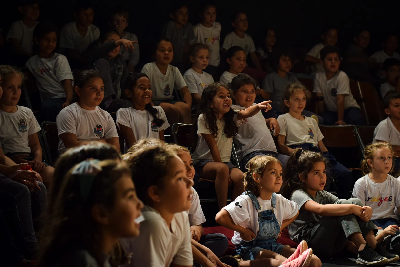 Plateia de estudantes uniformizados assistindo a uma sessão de teatro