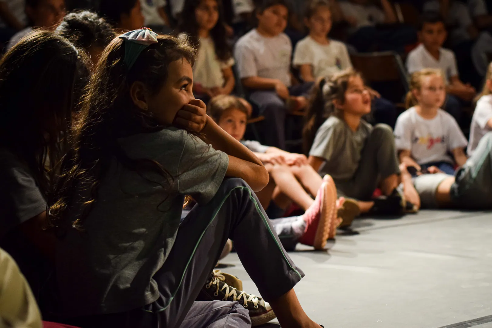 Crianças sentadas no chão do teatro durante uma sessão