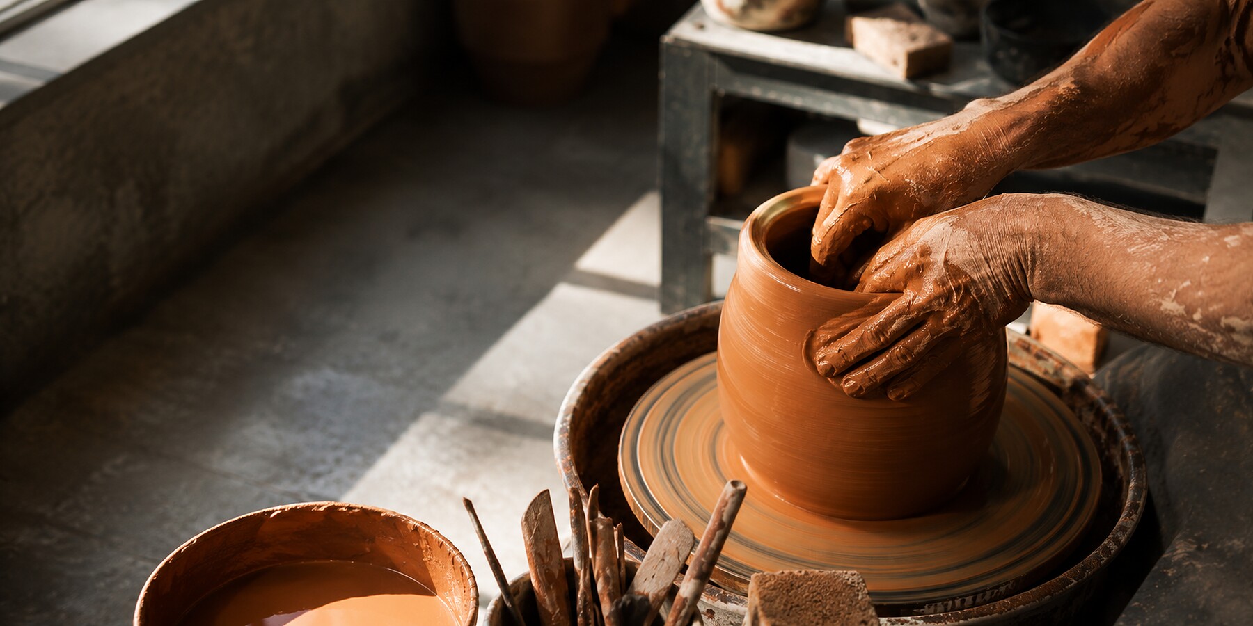 Mãos moldando peça artesanal em ateliê